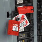 Cadenas de consignation compact rouge nylon avec étiquette Locked Out sur armoire électrique