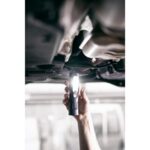 Lampe torche LED rechargeable tenue sous un véhicule éclairant la zone de travail