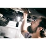 Lampe torche LED rechargeable noire sous véhicule avec faisceau lumineux orienté vers le dessous