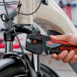 Pince à dénuder multifonction rouge et noire sur câble de vélo