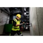 Projecteur LED sans fil sur chantier fixé contre un mur en béton avec opérateur en tenue haute visibilité