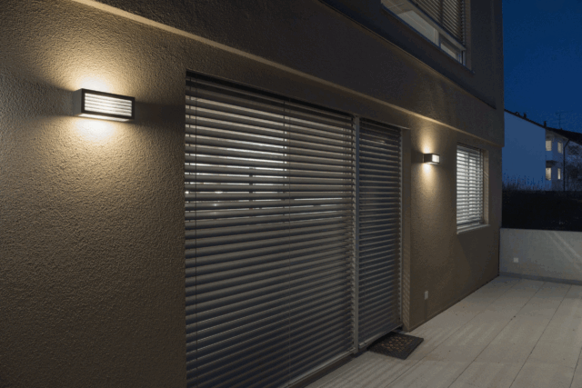 Applique extérieure LED anthracite rectangulaire fixée au mur éclairant une façade
