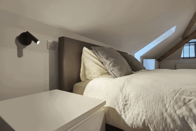 Applique murale LED noire orientable avec interrupteur près du lit