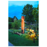 Spot à poser extérieur noir cylindrique éclairant un massif de jardin