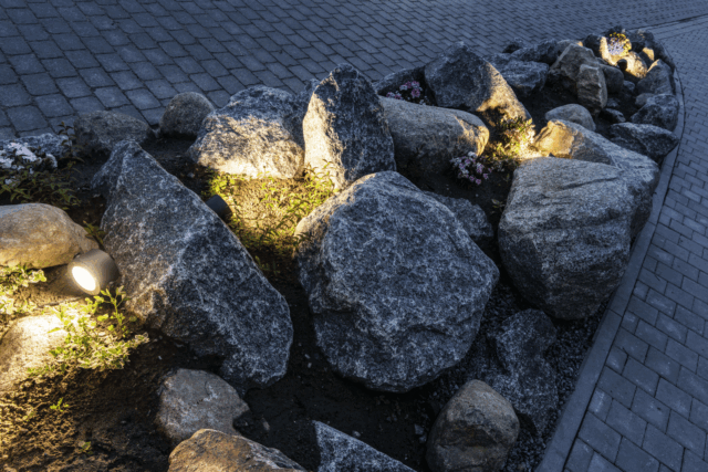 Spot de jardin sur piquet anthracite orientable éclairant des rochers près d un chemin
