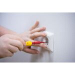 Tournevis isolé slimVario en usage sur prise murale avec embout rouge et manche jaune
