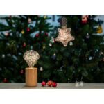 Lampe en bois avec ampoule étoile allumée près d’un sapin