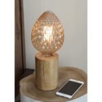 Lampe en bois avec ampoule ovoïde allumée près d’un téléphone