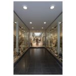 Galerie intérieure éclairée par des luminaires ronds au plafond