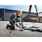 Opérateur tenant une meuleuse près d’une structure métallique sur un chantier