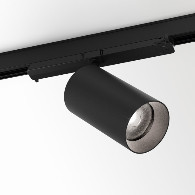 Projecteur cylindrique noir incliné sous un adaptateur de rail