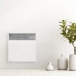 Convecteur blanc fixé au mur près d’une plante dans une pièce
