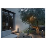 Bornes anthracite allumées le long d’une terrasse et d’un chemin dans un jardin